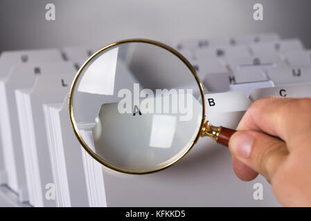 Investigating documents with magnifying glass over black background Stock Photo