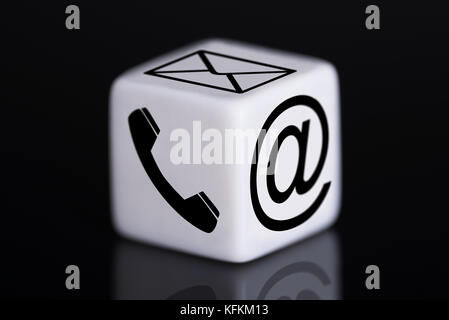Closeup of white dice with mail and phone icons against black background Stock Photo