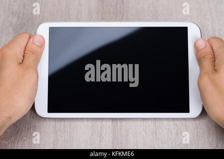 Cropped image of hands holding smartphone at wooden table Stock Photo
