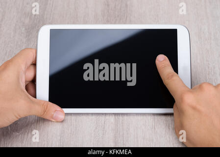 Cropped image of hands holding smartphone at wooden table Stock Photo