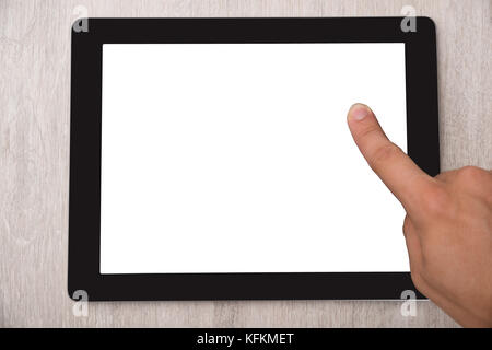 Cropped image of finger touching digital tablet at wooden table Stock Photo