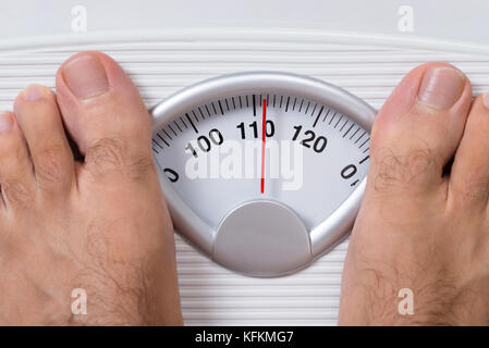 Closeup of man's feet on weight scale Stock Photo