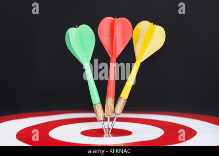 Closeup of darts on target isolated over black background Stock Photo