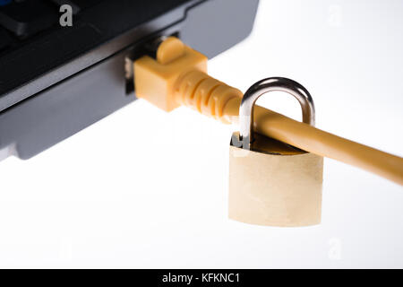 Closeup of padlock attached to plug in laptop isolated over white background Stock Photo