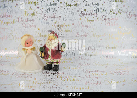 Christmas photography image of old vintage hand made fairy xmas tree topper and Santa Claus in white and gold with festive writing on shiny background Stock Photo