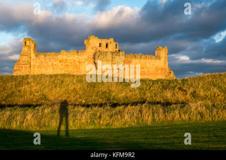 Dusk sun light on wall of 14th century ruined Tantallon Castle, North Berwick, East Lothian coast, Scotland, with long shadow of the photographer Stock Photo