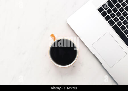 Laptop and yellow coffee cup workspace overhead on white marble background Stock Photo