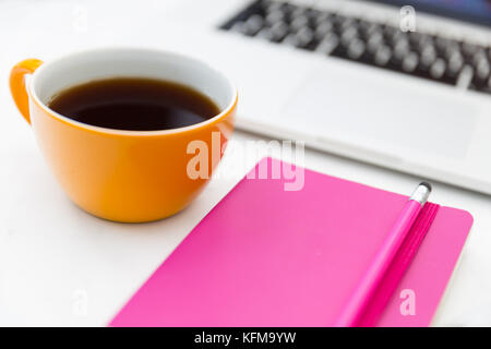 Laptop computer pink notebook and coffee cup in office workspace Stock Photo