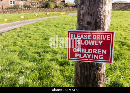 Sign on a village green, Please drive slowly. Children Playing. Stock Photo