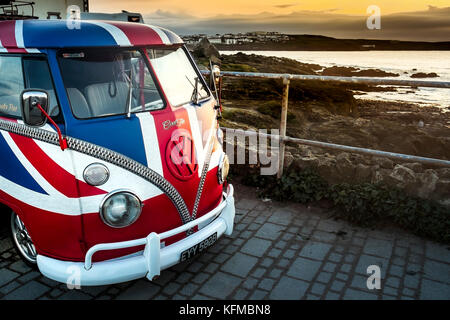 A vintage Volkswagen Camper van painted in the colours of the Union Flag parked at little Fistral in Newquay Cornwall. Stock Photo