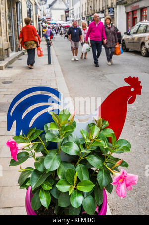 France, Brittany, Morbihan, Vannes, a gallic rooster decoratively shares a pot with petunias in the historic city center of Vannes Stock Photo