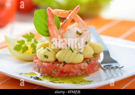 Italian gnocci and tiger prawns on tomato ragout with basil and olive oil Stock Photo