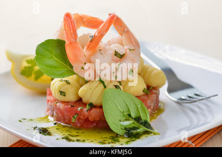 Italian gnocci and tiger prawns on tomato ragout with basil and olive oil Stock Photo