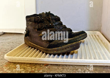 Dusty well worn hiking boots, on staircase in front of apartment door, in an old condominium socialist realism style in 1950s. Vienna, Austria, Europe Stock Photo