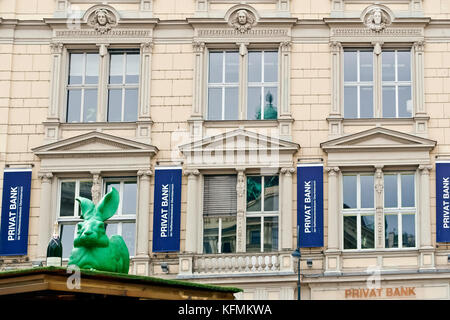 Privat bank at Operngasse. On rooftop: big green plastic rabbit sculpture, Cracking art project Installation. Big bottle of Champagne. Vienna, Austria Stock Photo