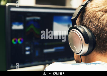 man doing video editing on computer with headphones on Stock Photo