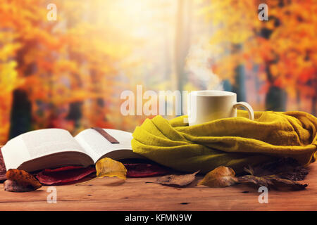autumn mood - opened book, scarf and hot drink on the table Stock Photo