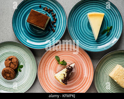 Set of various cakes on plates on grey background Stock Photo