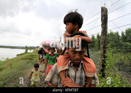 Myanmar: Rohingya refugees fleeing military operation in Myanmar’s Rakhine state, walk along the Myanmar-Bangladesh border fence near Maungdaw to take shelter into Bangladesh on September 7, 2017. Over half a million Rohingya refugees from Myanmar’s Rakhine state, have crosses into Bangladesh since August 25, 2017 according to UN. The Myanmar military's latest campaign against the Rohingyas began after the attack on multiple police posts in Rakhine state. © Rehman Asad/Alamy Stock Photo Stock Photo