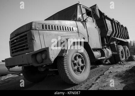 A black and white image of a rusty old truck with bullet holes in the door. Stock Photo