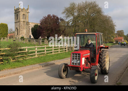 Man driving old red vintage tractor through village of Bugthorpe on Wolds Vintage Group Road Run, an annual charity event - Yorkshire, England, UK. Stock Photo