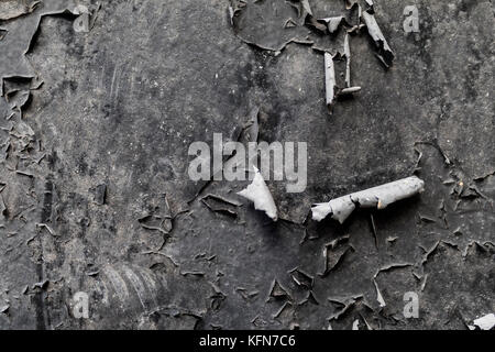 Peeling black paint on a dirty old metal industrial surface creates a grunge textured background in the UK Stock Photo