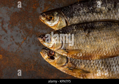 Dried fish. Salty dry river fish on a rusty metal plate background. Stock Photo