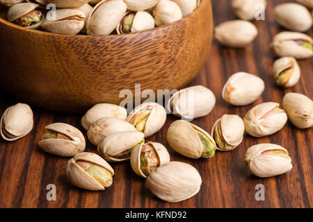 Pistachios nuts in shell on wooden bowl Stock Photo