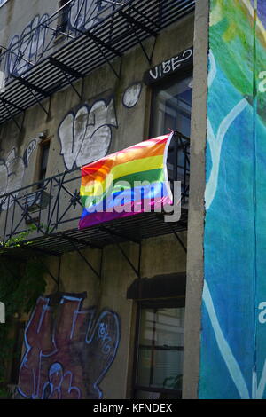 Gay pride flag (rainbow flag) hanging on the fire escape of an old apartment building, Chelsea, New York City, NY, USA Stock Photo