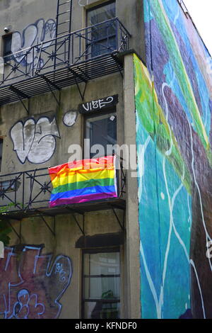 Gay pride flag (rainbow flag) hanging on the fire escape of an old apartment building, Chelsea, New York City, NY, USA Stock Photo