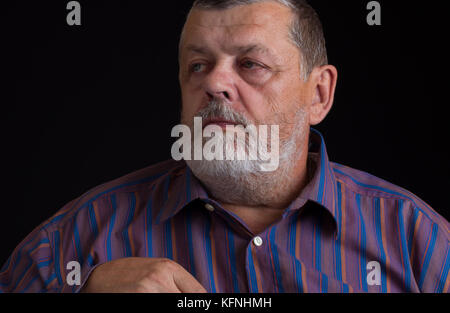 Nice portrait of a thoughtful senior man in striped shirt Stock Photo