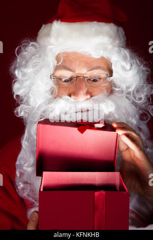 Close-up of santa looking in gift over black background Stock Photo