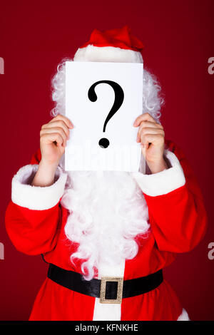 Portrait of a santa holding question mark in front of his face Stock Photo