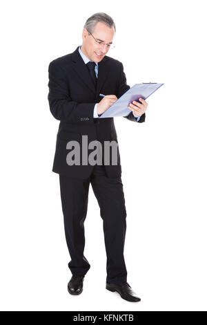 Happy Mature Businessman Writing On Clipboard Over White Background Stock Photo