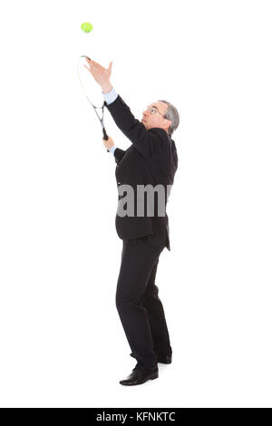 Mature Businessman Holding Tennis Racket And Ball Over White Background Stock Photo