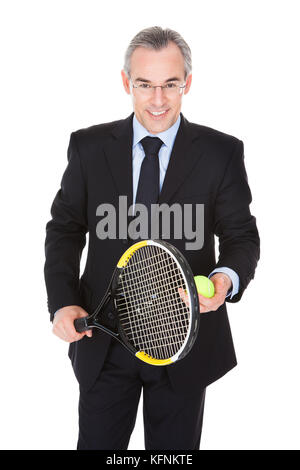 Mature Businessman Holding Tennis Racket And Ball Over White Background Stock Photo