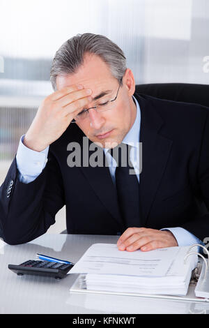Mature Businessman Having Headache Sitting At Desk In Office Stock Photo