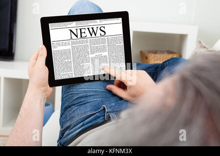Close-up Of a Mature Man reading news on digital tablet Stock Photo