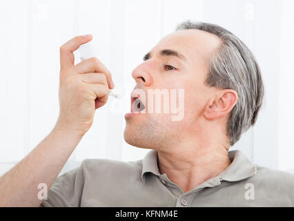 Man with asthma using an asthma inhaler for preventing attacks Stock Photo