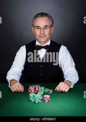 Portrait of a croupier with gambling chips on table Stock Photo