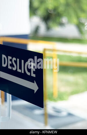Sliding door sign in spanish on glass door with ramp and railing on the background for wheelchair access and people with disabilities Stock Photo