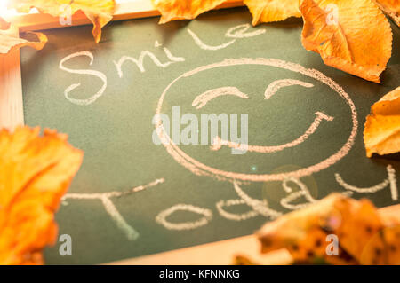 Smile Today message on Chalk Board, decorated with autumn leafs Stock Photo