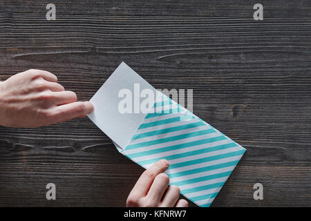 two hands opening a striped letter on wooden table Stock Photo