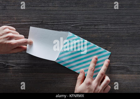 hands opening striped letter on dark wooden surface Stock Photo