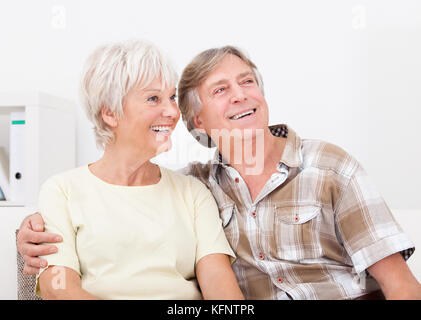 Portrait Of Happy Senior Couple Sitting Together Side By Side Looking Away Stock Photo