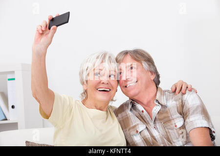 Senior Woman Using Mobile Phone Photographing Self With Husband Stock Photo