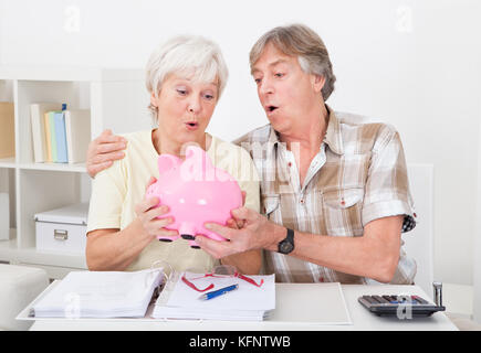 Portrait Of Senior Couple Saving Money In The Pink Piggybank Stock Photo