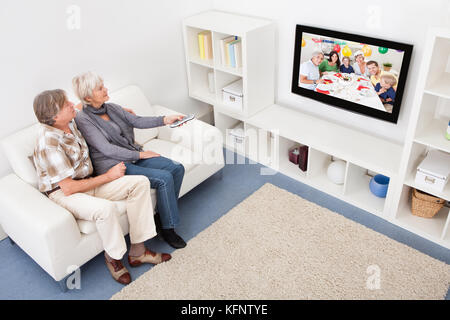 Senior Couple In Living Room Using Remote Control In Front Of Television Stock Photo