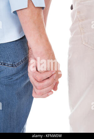 Close-up Of Senior Couple Hands Holding Each Other Over White Background Stock Photo