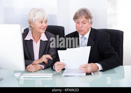 Mature Businessman And Businesswoman Looking At Computer Stock Photo